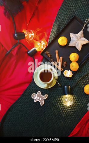 Da sopra composizione con mandarini freschi aromatici e spezie posto vicino tazza di tè caldo e pan di zenzero uomo con elementi decorativi e garland on Foto Stock