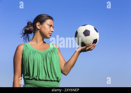 Giovane donna colombiano calcio tenendo a portata di mano con cielo blu Foto Stock