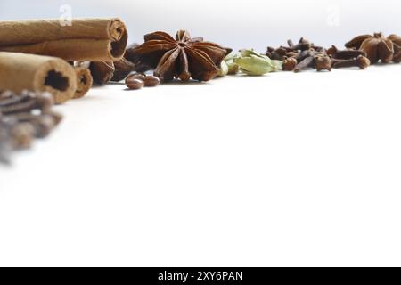 Spezie invernali o ingredienti da forno per Natale, cannella, cardamomo, chiodi di garofano, stelle di anice, su sfondo bianco con spazio di copia Foto Stock