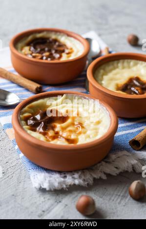 Budino di riso al forno sutlac per dessert lattiginoso turco in casseruola con bastoncini di cannella e nocciole tritate Foto Stock