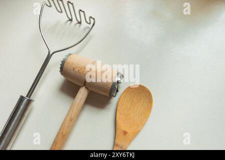 Utensili da cucina per schiacciare patate e tenderizer per carne con cucchiaio di legno, vista dall'alto Foto Stock