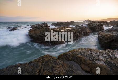 Onde che scivolano sulle rocce vicino al mare, lunga esposizione, paesaggio costiero al tramonto, Playa Cocalito, costa del Pacifico, penisola di Nicoya, provincia di Puntarenas, Foto Stock