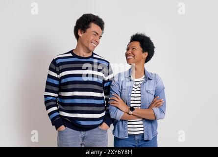 Ritratto di una giovane coppia allegra sorridente e che si guarda mentre posa su sfondo bianco Foto Stock