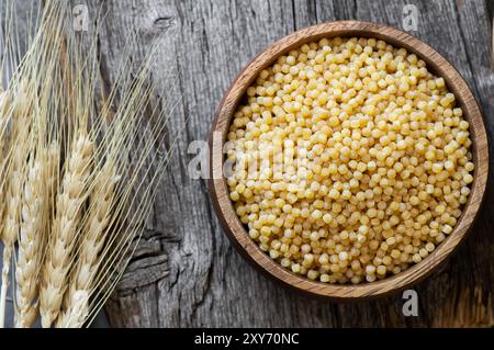 Couscous crudo in ciotola su sfondo di legno con affettati, concetto di cibo crudo Foto Stock
