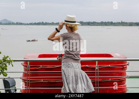 Tonle SAP/Mekong Crociere : elegante signora anziana sul ponte prendisole della nave da crociera per ammirare il paesaggio della vita locale e delle sponde, navi che navigano lungo il fiume Foto Stock