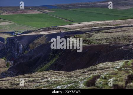 Persone che camminano lungo il canyon di un fiume vicino alla cascata Hengifoss in Islanda Foto Stock