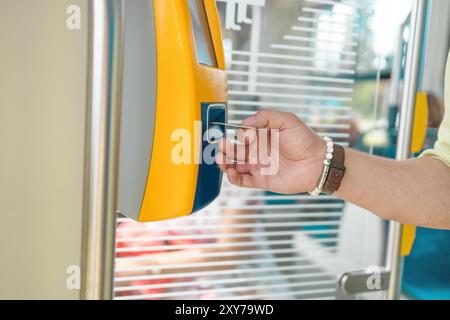 Pagamento semplice per il trasporto. L'uomo consegna il biglietto a un passeggero in tram o in autobus, utilizzando il distributore automatico di biglietti Foto Stock