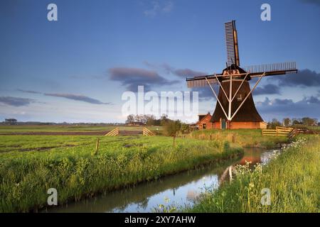 Mulino a vento olandese si riflette nel fiume in alba la luce solare, Olanda Foto Stock