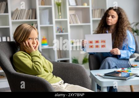 Giovane logopedista che lavora con un ragazzo biondo ed entrambi sembrano coinvolti Foto Stock