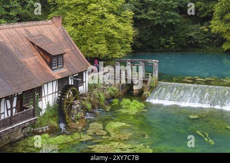 Blautopf Blaubeuren con monumento industriale Hammerschmiede, sorgente del piccolo fiume Blau in un paesaggio con foresta. Primavera carsica, geotopo e geo Foto Stock