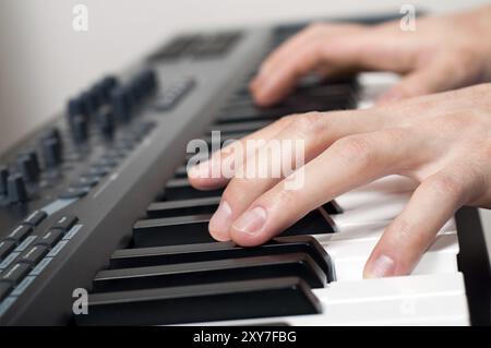 Primo piano di mani maschili che suonano il pianoforte in studio Foto Stock