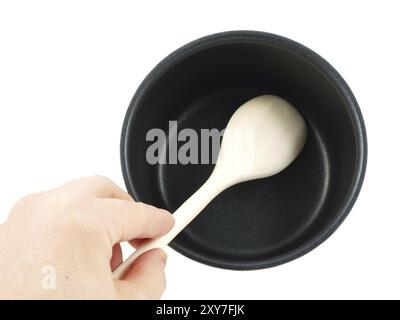 Bollitore in acciaio inox, con spatola in legno e mano umana, isolato su sfondo bianco Foto Stock