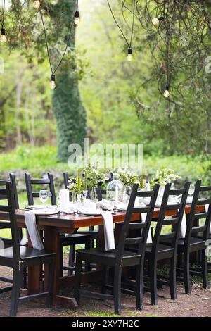 La decorazione della tavola di nozze con vasi di cristallo, fiori e rami in stile botanico nel giardino Foto Stock