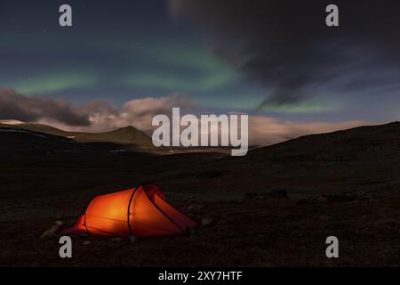 Aurora boreale (Aurora boreale) sopra la tenda illuminata, Rapadalen, Parco Nazionale Sarek, sito Patrimonio Mondiale dell'Umanità della Laponia, Norrbotten, Lapponia, Svezia, settembre Foto Stock