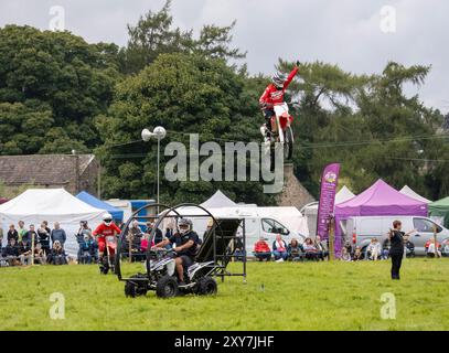 Uno stunt man su una bicicletta che va oltre un salto al Reeth Show di Swaledale, Yorkshire Dales, Regno Unito. Foto Stock