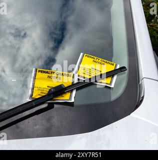 Due biglietti di penalità addebitati sullo schermo del finestrino di un'auto Foto Stock