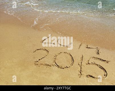 Il nuovo anno 2015 è in arrivo, le iscrizioni 2014 e 2015 su una spiaggia sabbiosa, l'onda copre le cifre 2014 Foto Stock