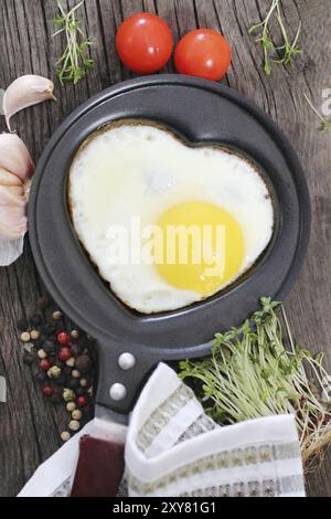 Uovo fritto nel cuore-forma sagomata con crescione, pomodoro, aglio e pepe Foto Stock