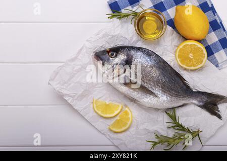 Crudo fresco Orate di mare il pesce con le fette di limone, sale, rosmarino e olio di oliva bianco sul tavolo di legno.il cibo sano concetto, vista dall'alto, spazio di copia Foto Stock