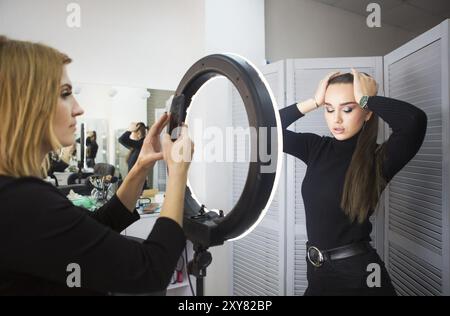 Make up Artist tenendo mobile photo per il modello con il trucco Foto Stock