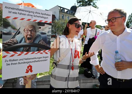 Erfurt, Germania. 28 agosto 2024. Mario Voigt (r), leader dello stato CDU e candidato principale per le elezioni statali, e Anna Lihs, membro del Consiglio di amministrazione dell'Associazione dei farmacisti della Turingia, parlano tra loro durante una manifestazione di protesta delle farmacie di fronte alla Cancelleria di Stato della Turingia. Vogliono protestare contro gli attuali piani di riforma del Ministro federale della sanità. I raduni si svolgeranno simultaneamente a Dresda ed Erfurt. Crediti: Martin Schutt/dpa/Alamy Live News Foto Stock