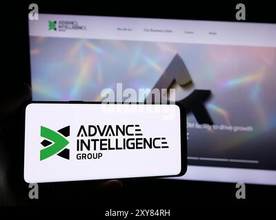 Persona che possiede uno smartphone con il logo della società Fintech di Singapore Advance Intelligence Group davanti al sito Web. Mettere a fuoco il display del telefono. Foto Stock