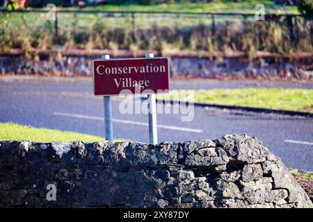 Cartello del villaggio di conversazione all'ingresso del villaggio di Cardross, il cartello mostra il tempo di muffa verde, muffa verde, muffa verde o alghe Foto Stock
