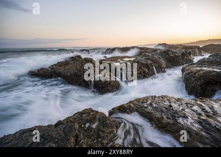 Onde che scivolano sulle rocce vicino al mare, lunga esposizione, paesaggio costiero al tramonto, Playa Cocalito, costa del Pacifico, penisola di Nicoya, provincia di Puntarenas, Foto Stock