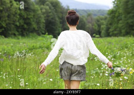 Felice bella bruna donna nel campo di camomilla, carino donna rilassata sul prato di fiori di primavera, natura, divertimento outdoor Foto Stock