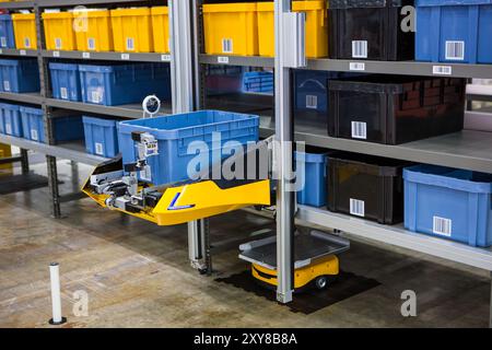 Robot autonomo che preleva i materiali da rack multistrato in un moderno magazzino industriale. Foto Stock
