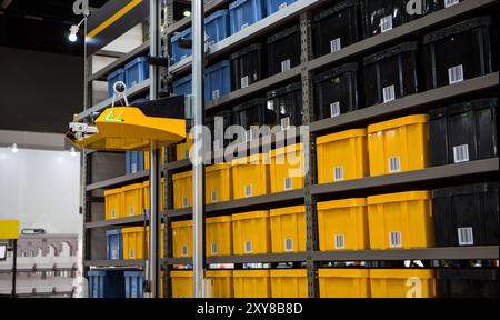 Robot autonomo che preleva i materiali da rack multistrato in un moderno magazzino industriale. Foto Stock