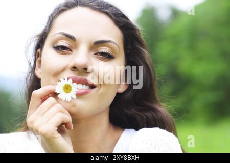 Felice bella bruna donna nel campo di camomilla, carino donna rilassata sul prato di fiori di primavera, natura, divertimento outdoor Foto Stock