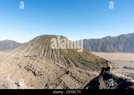 Viaggiatore seduto nel cratere del monte Bromo, Giava, Indonesia Foto Stock