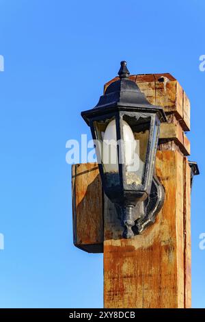 Vecchio lampione in legno con vetro rotto con cielo blu sullo sfondo Foto Stock