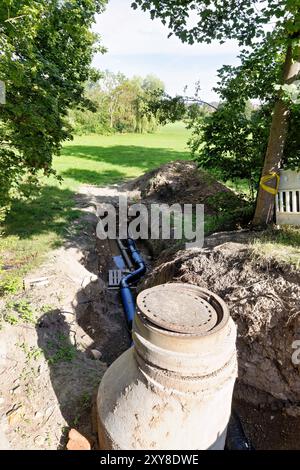 Lavorare su un sistema di drenaggio per il sistema di drenaggio urbano con un nuovo sistema di tubazioni Foto Stock