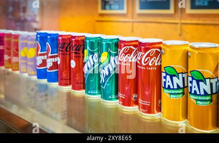 Lattine di Fanta, Coca-Cola e Sprite sullo scaffale di un negozio. Lattine di bevande di diversi gusti a stock. drin morbido e fortemente carbonato analcolico Foto Stock