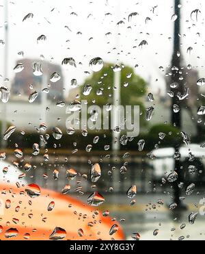 Gocce di pioggia sul finestrino di un'auto con auto sfocate su una strada cittadina, Shanghai, Cina. Concetto di viaggio e sviluppo. Foto Stock