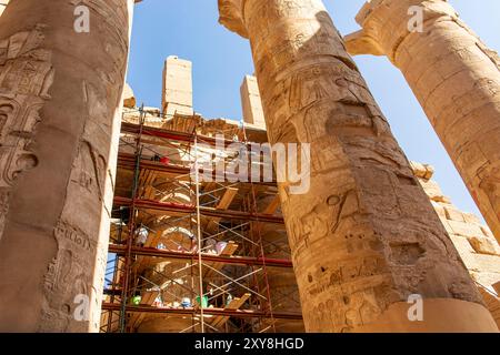 Luxor, Egitto; 16 gennaio 2024: Archeologi che esaminano meticolosamente i colossali pilastri della sala ipostila di Karnak. Ci portano più vicini alla rovina Foto Stock