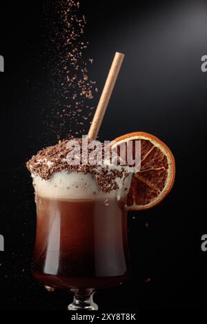 Cocktail al cioccolato con panna montata cosparsa di gocce di cioccolato e guarnita con una fetta di arancia secca. Foto Stock