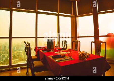 Bangkok, Tailandia - 11 febbraio 2024: Interni moderni e accoglienti di colore rosso, servizi da pranzo vuoti. Cena di lusso all'hotel Baiyoke Sky. Bangk Foto Stock