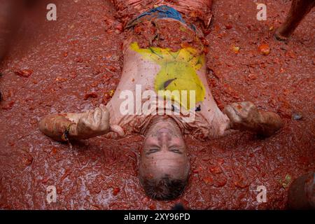 Valencia, Spagna. 28 agosto 2024. I partecipanti al festival della Tomatina di Buñol si coprono con pomodori schiacciati durante il festival della Tomatina. Ancora una volta, il popolare festival la Tomatina si tenne nella città valenciana di Buñol. Sei camion con 120.000 chili di pomodori sono stati lanciati tra i 22.000 partecipanti al festival. (Foto di David Canales/SOPA Images/Sipa USA) credito: SIPA USA/Alamy Live News Foto Stock