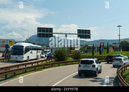 Progni, Italia - 8 giugno 2023: I veicoli navigano in un trafficato interscambio autostradale, con colline lontane incorniciate da un cielo azzurro. Foto Stock