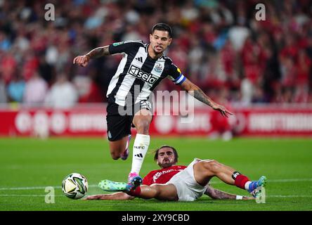 Bruno Guimaraes del Newcastle United in azione contro Jota Silva del Nottingham Forest durante la partita del secondo turno della Carabao Cup al City Ground di Nottingham. Data foto: Mercoledì 28 agosto 2024. Foto Stock