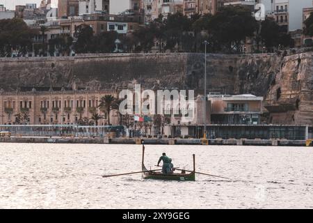 Due uomini che regnano un tradizionale dgħajsa maltese nel porto tra la Valletta e Birgu, Malta Foto Stock