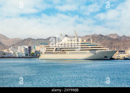 Il panorama della passeggiata di Mutrah con le montagne e la nave da crociera turistica ancorata nel porto di Mascate, Sultanato Oman Foto Stock