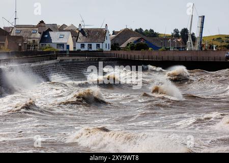 Mari tempestosi che creano enormi onde contro gli scalini all'ingresso del porto di Maryport Foto Stock