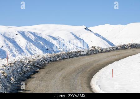 Una strada tortuosa e innevata si snoda attraverso un pittoresco paesaggio invernale, invitante esplorazione Foto Stock