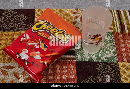 Cheetos croccante con un bicchiere di latte. Charles Elmer Doolin inventò Cheetos nel 1948, Frito-Lay è una filiale della PepsiCo. Chester Cheetah-Mascot! Foto Stock