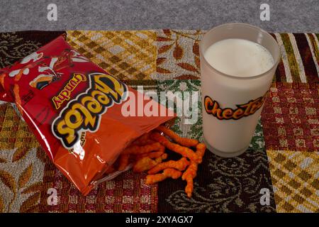 Cheetos croccante con un bicchiere di latte. Charles Elmer Doolin inventò Cheetos nel 1948, Frito-Lay è una filiale della PepsiCo. Chester Cheetah-Mascot! Foto Stock