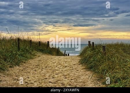 Attraversamento delle dune sulla spiaggia di Blavand, Danimarca, affacciata sul mare. Tramonto all'orizzonte Foto Stock